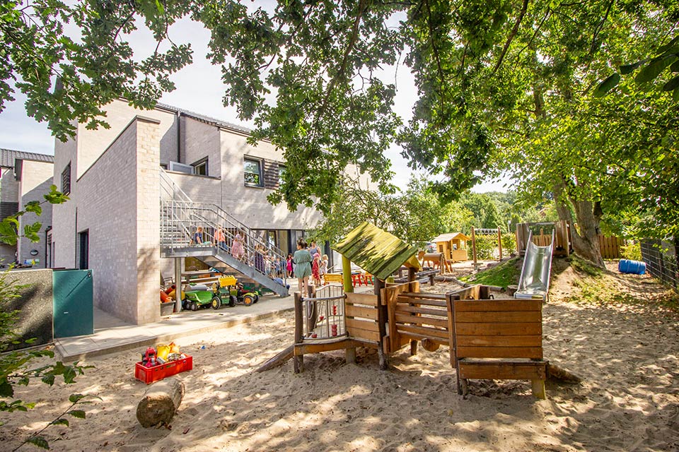 Kita Bärenhöhle: Spielplatz unter Bäumen